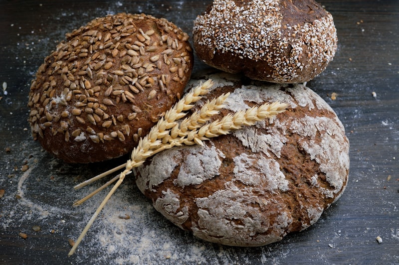 Assortment of freshly baked crusty artisan bread and sourdough loaves on a wooden baker's rack, rustic setting